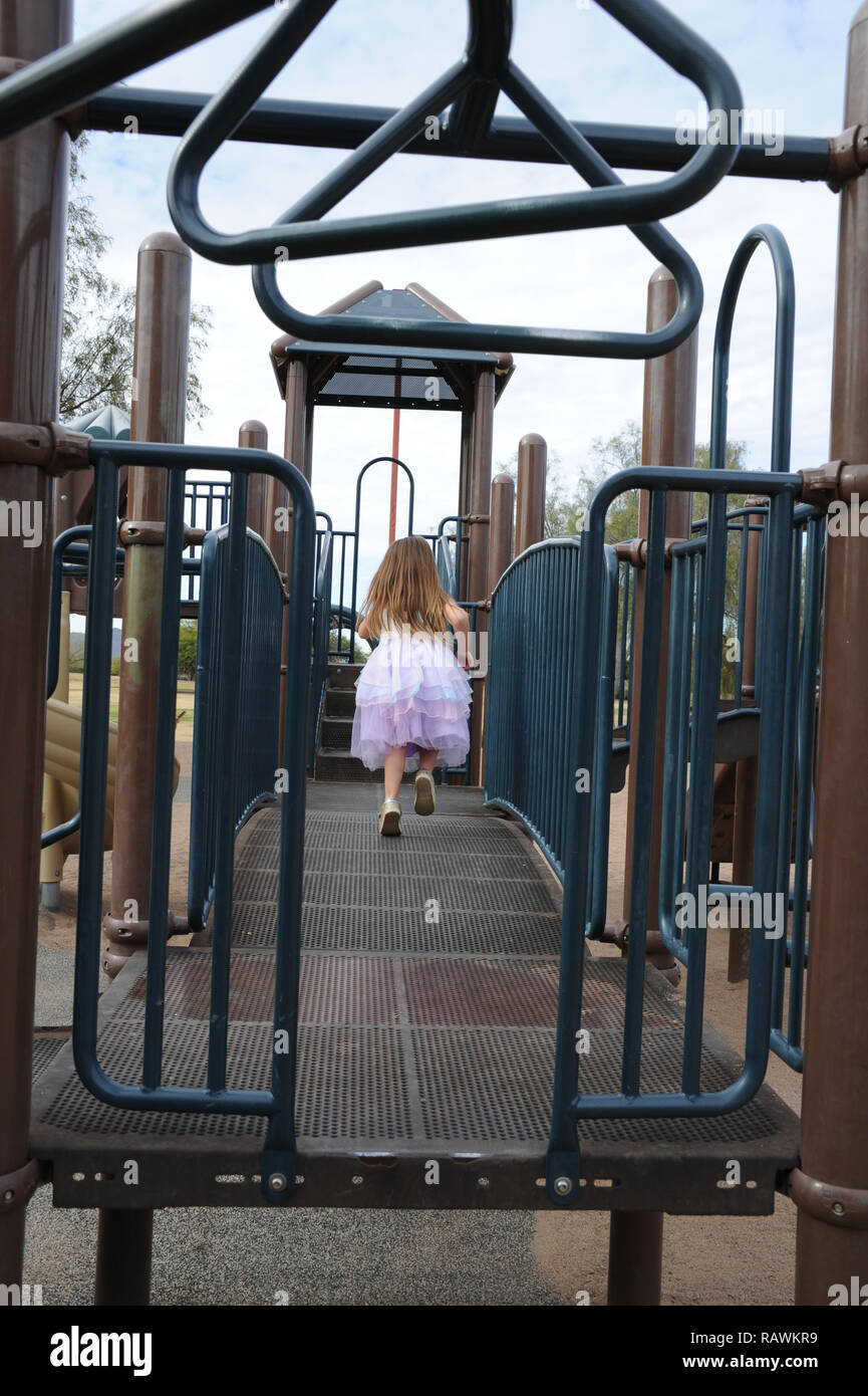 Giovane ragazza in esecuzione su attrezzature per parchi giochi in una principessa abito Foto Stock
