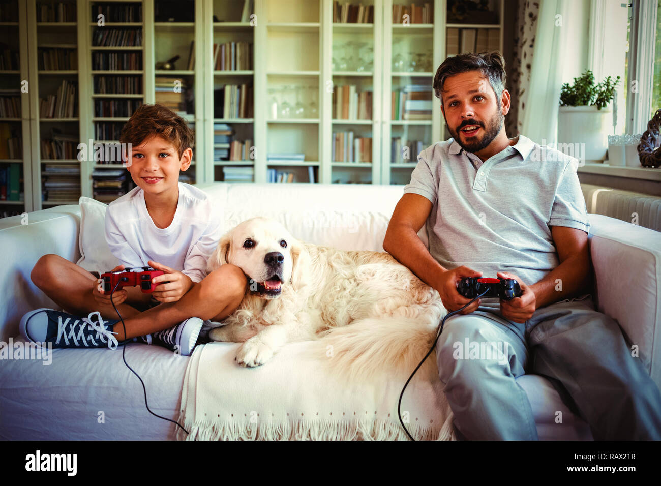 Padre e Figlio seduto sul divano con il cane e la riproduzione di video giochi Foto Stock