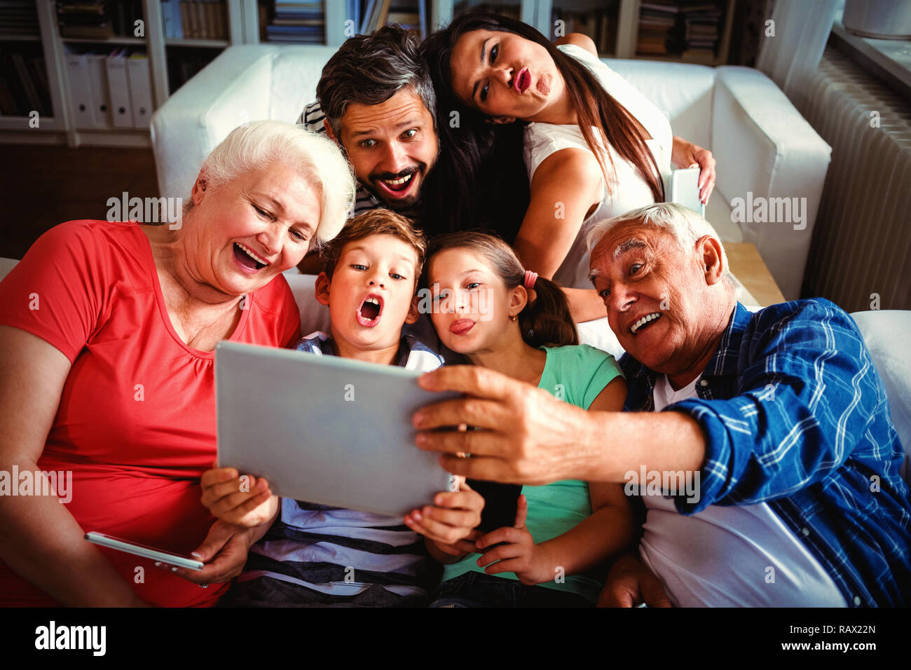 Multi generazione famiglia prendendo un selfie sulla tavoletta digitale in salotto Foto Stock