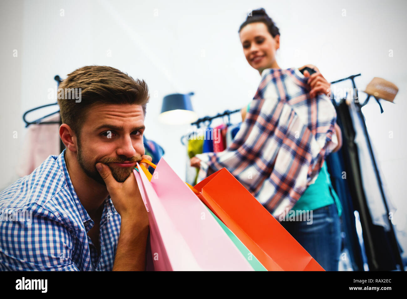 Annoiato uomo con borse per lo shopping e la donna dal portabiti Foto Stock