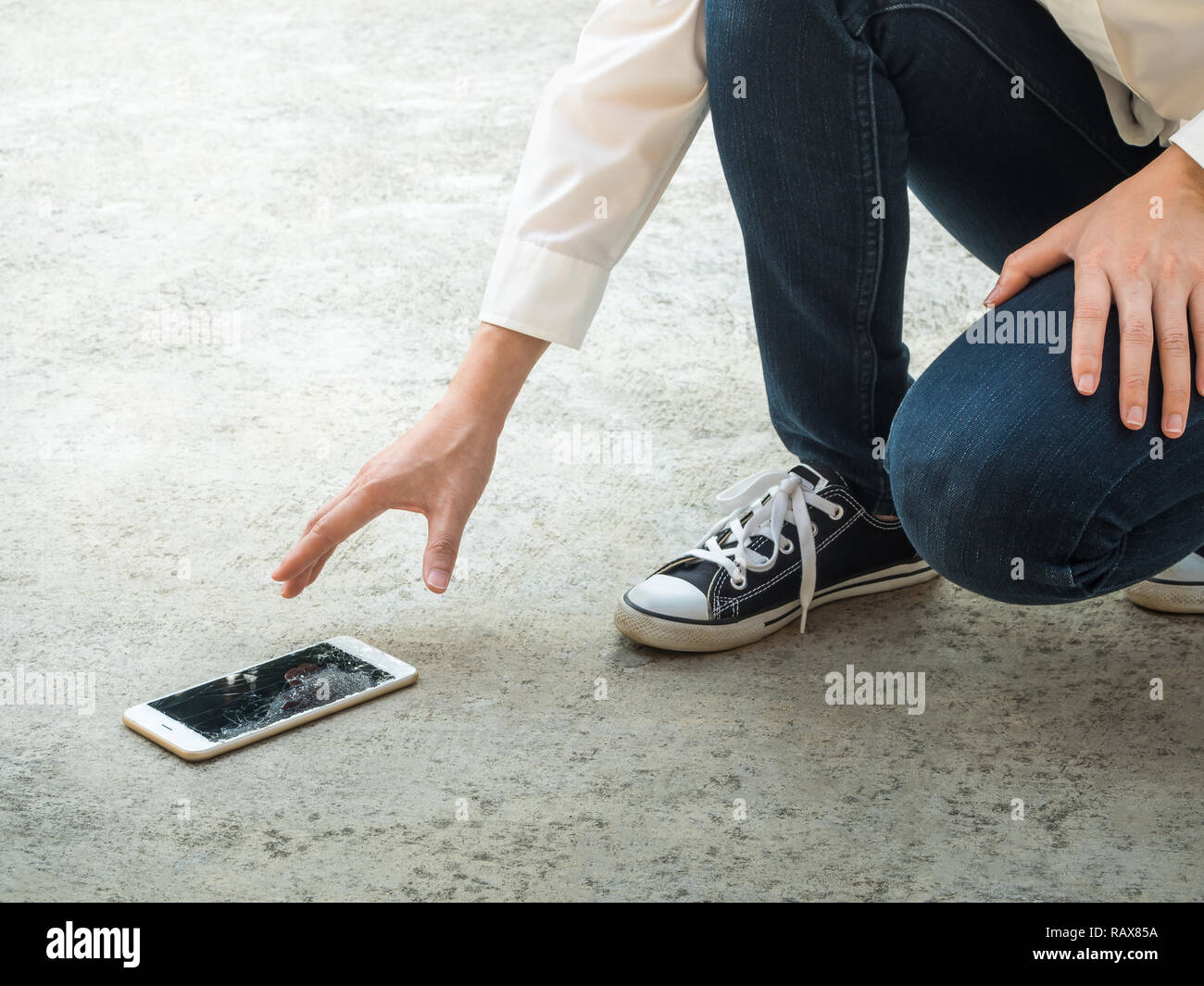 Persona Picking rotto Smart Phone (schermo incrinato) della Terra Foto Stock