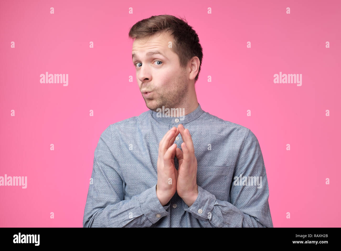 Astuzia tricky uomo maturo pensare guardando con mano insieme su sfondo rosa. Concetto di gioco sleale Foto Stock