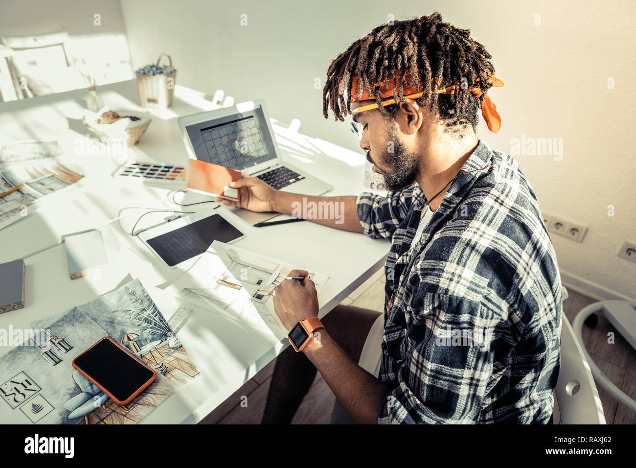 Interior designer con dreadlocks che indossa la fascia rossa schizzi di disegno Foto Stock