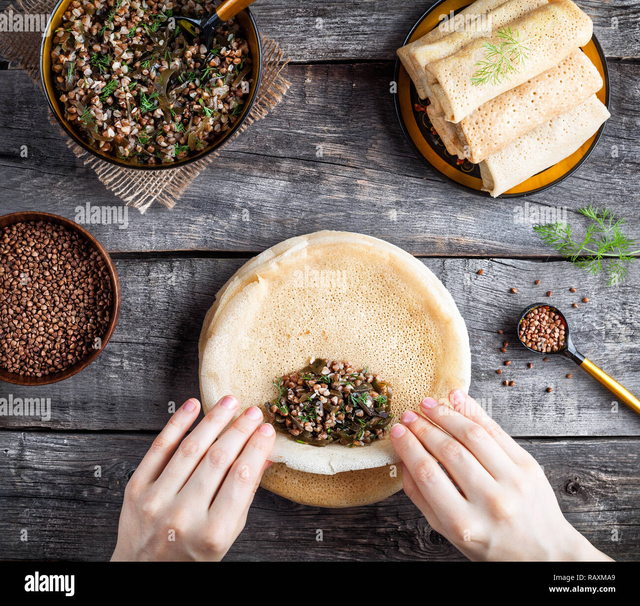 Donna russa di rotolamento vegane frittelle di grano saraceno e Laminaria servita in stile rustico sulle vacanze Shrovetide Foto Stock