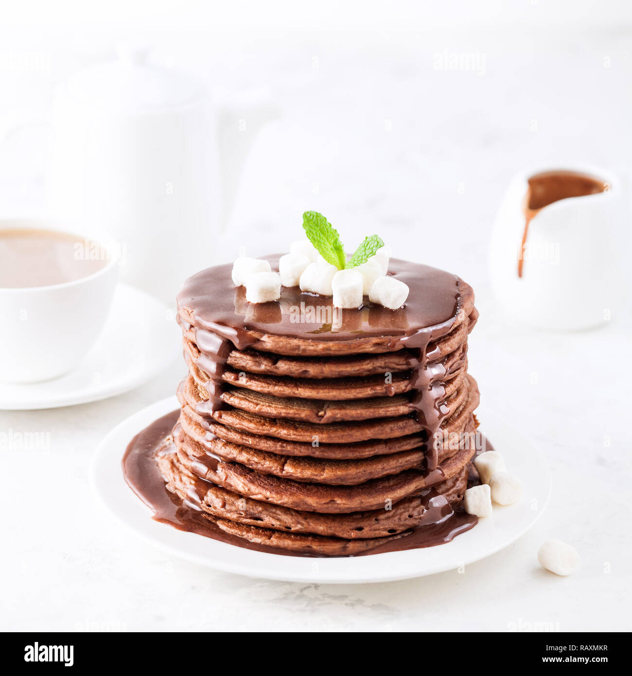 Frittelle di cioccolato con marshmallows sulla parte superiore su sfondo bianco a colazione Foto Stock