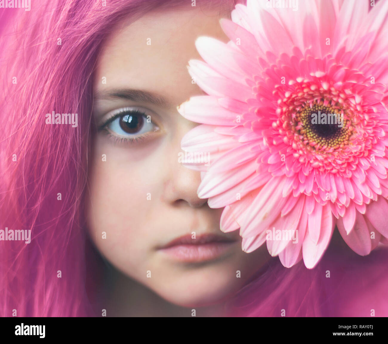 Ritratto di una piccola ragazza con i capelli rosa e fiore rosa oltre il suo occhio Foto Stock