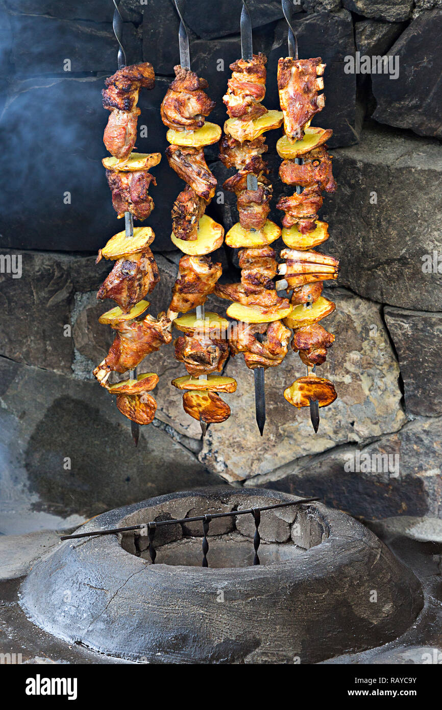 Agnello e spiedini di pollo con patate sullo spillone, al di fuori del forno tandoori. Foto Stock