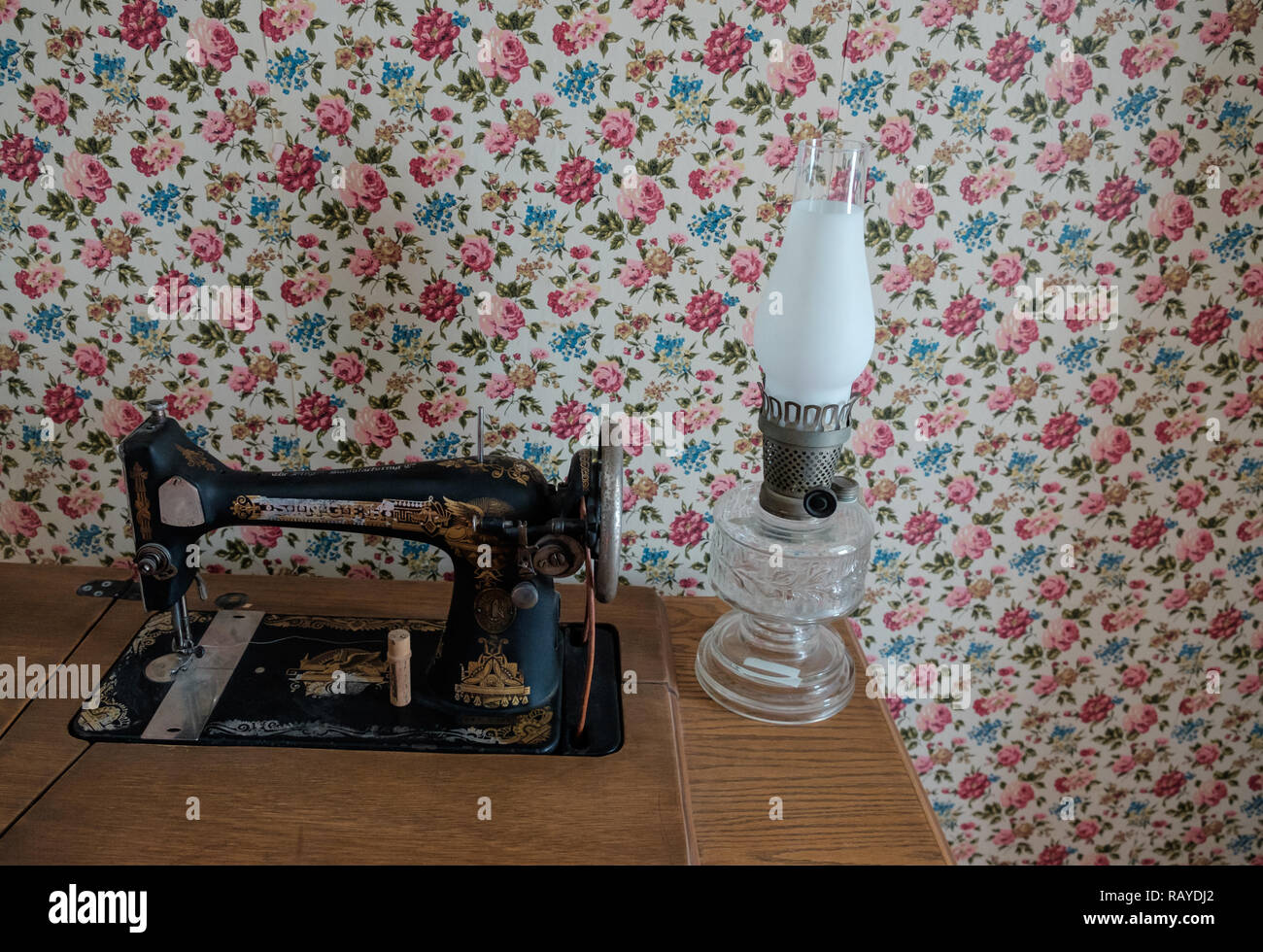 Vintage Singer macchina da cucire & antico salone di vetro spia sul tavolo boscoso con vintage carta da parati in stile vittoriano. Borgo di castagno, McKinney, Texas. Foto Stock