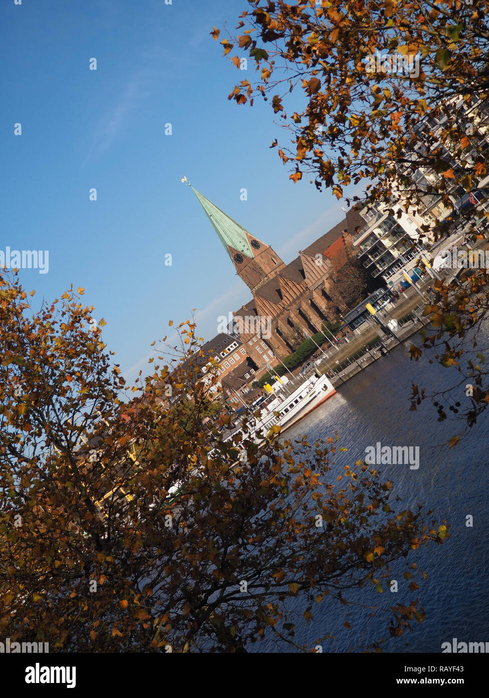 Bremen, Germania - Fiume Weser con San Martini chiesa incorniciata da alberi in primo piano con orizzonte inclinato Foto Stock