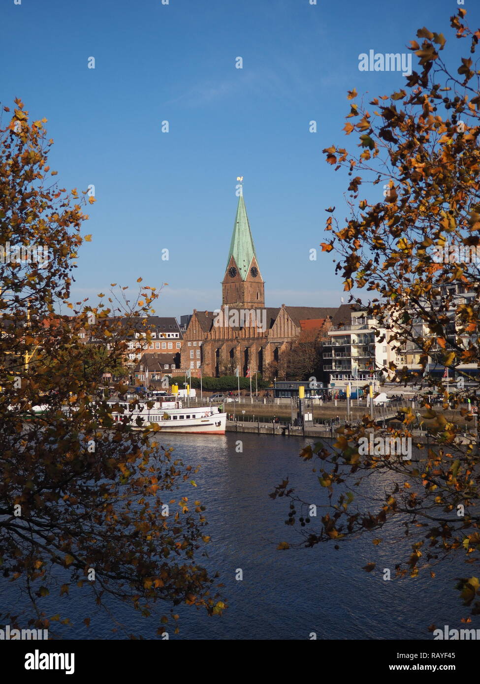 Bremen, Germania - Fiume Weser con San Martini chiesa incorniciata da alberi in primo piano Foto Stock