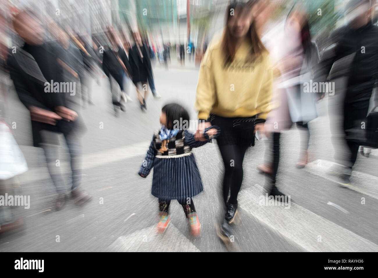 bambino cinese sulla mano delle madri tra molte persone in città Foto Stock