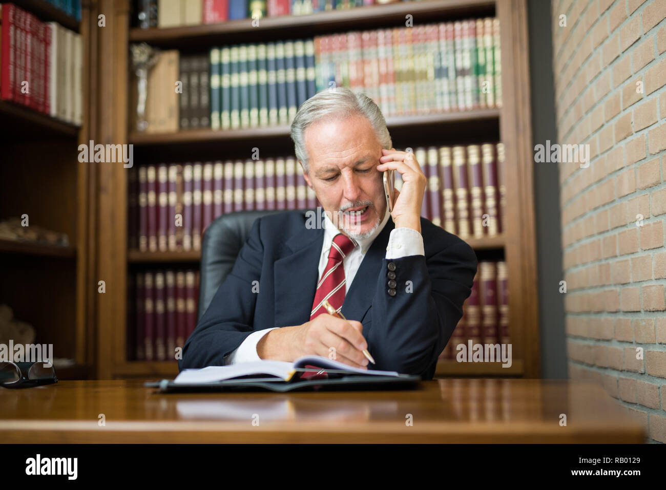 Senior avvocato imprenditore leggendo le sue note nell'ufficio a casa. Busy business man parlando al telefono Foto Stock