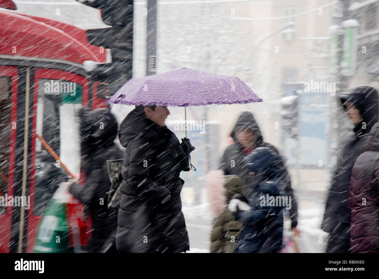 A Belgrado, in Serbia - Dicembre 15, 2018: Una donna camminare sotto ombrellone in forte nevicata in città strada folla Foto Stock