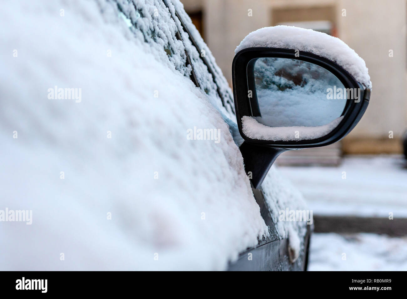 Close-up di coperta di neve auto specchio di ala. Foto Stock