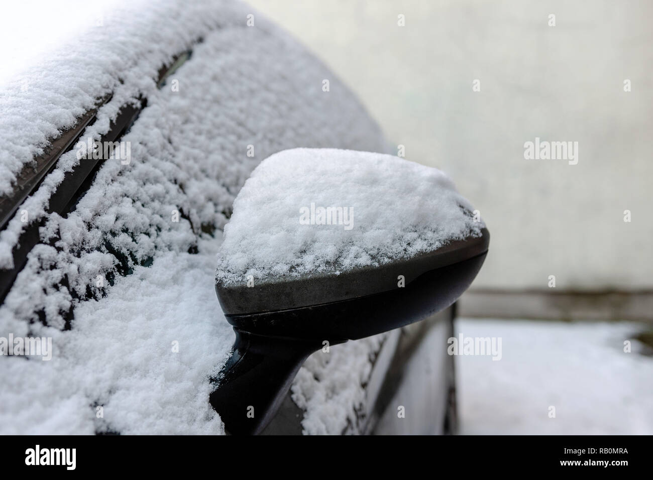 Close-up di coperta di neve auto specchio di ala. Foto Stock
