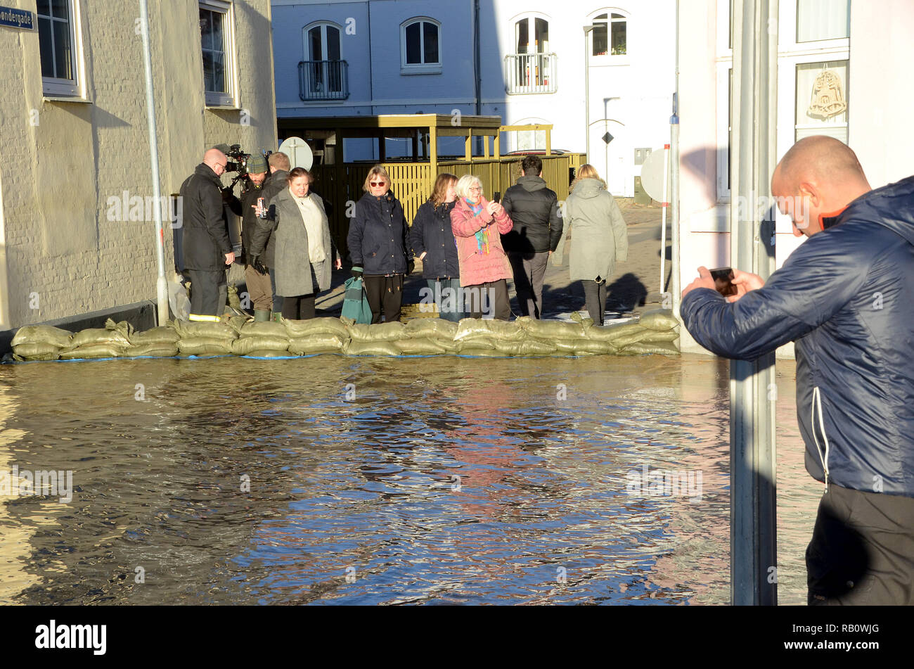 Sonderborg, Danimarca - 2 Gennaio 2019: una strada è stata bloccata con sacchi di sabbia a causa di una mareggiata. Le persone in piedi dietro i sacchi di sabbia a guardare il flo Foto Stock