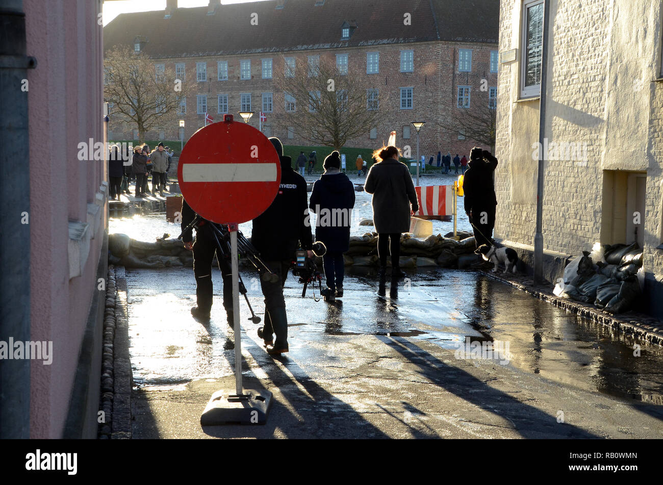 Sonderborg, Danimarca - 2 Gennaio 2019: una strada è stata bloccata con sacchi di sabbia a causa di una mareggiata. Le persone in piedi dietro i sacchi di sabbia a guardare il flo Foto Stock