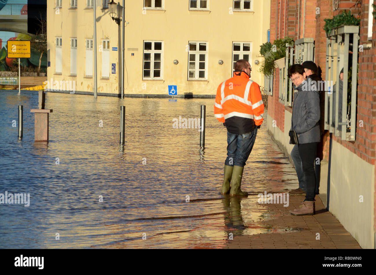 Sonderborg, Danimarca - 2 Gennaio 2019: durante una mareggiata il proprietario di una casa allagata discute egli situazione con alcuni dei suoi affittuari mentre watc Foto Stock