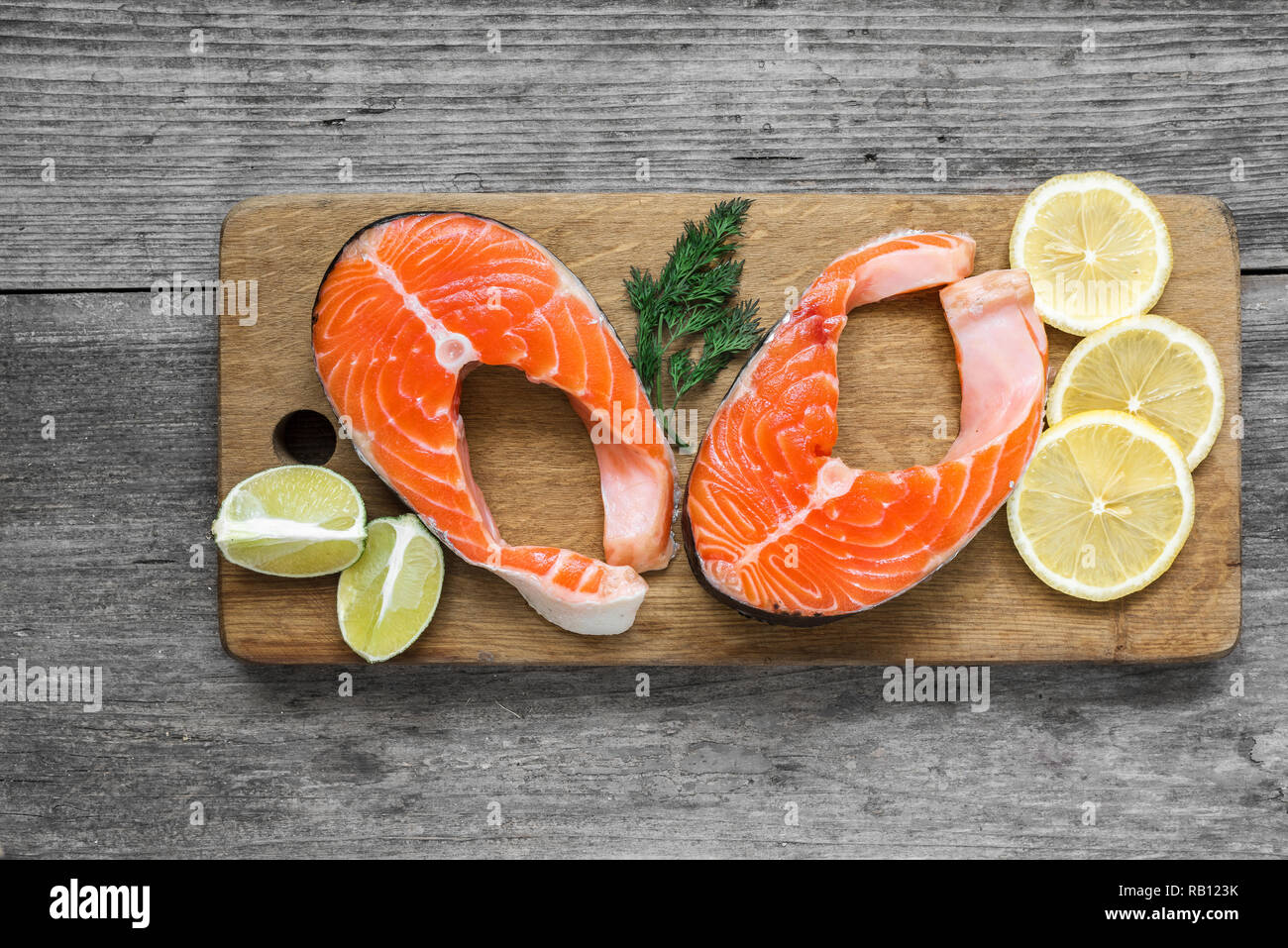 Bistecca di salmone ricco di omega 3 olio sul tagliere di legno su legno rustico sfondo. Un sano e la dieta alimentare. vista superiore Foto Stock