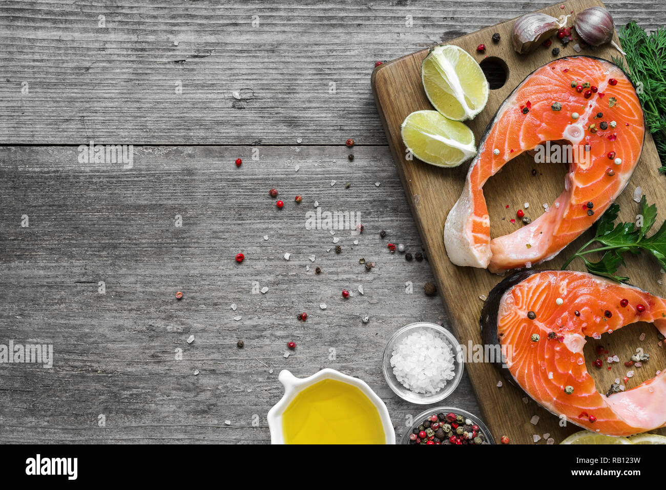 Bistecca di salmone ricco di omega 3 olio con erbe e spezie sul tagliere di legno su legno rustico sfondo. Un sano e la dieta alimentare. vista superiore con cop Foto Stock