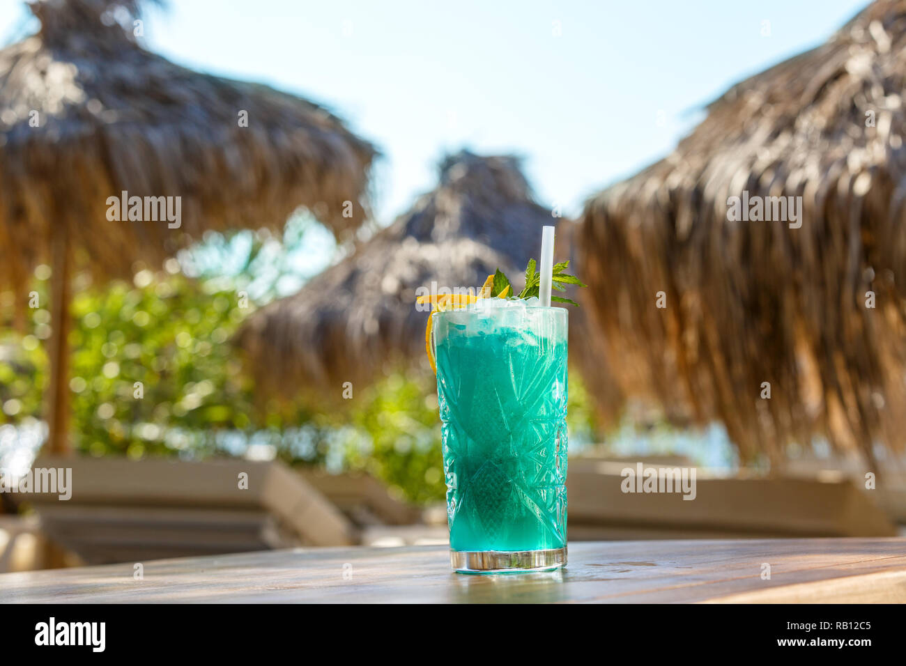 Vetro cristallo di verde drink sulla spiaggia tabella Foto Stock