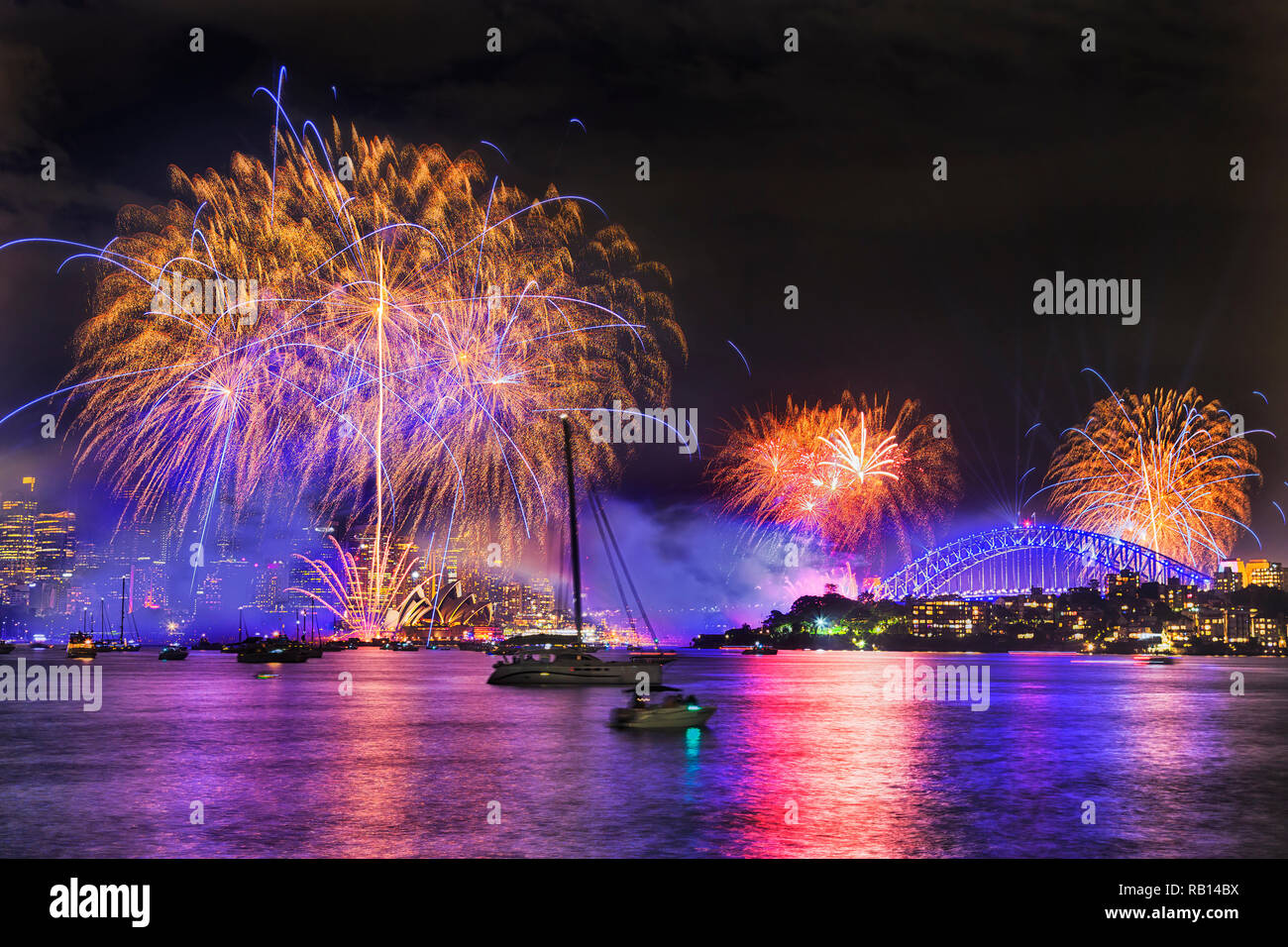 Disegno calligrafico nel buio della mezzanotte del cielo della città di Sydney durante il nuovo anno fuochi d'artificio con sprazzi di luce colorate sfere sopra porto acqua, CBD towe Foto Stock