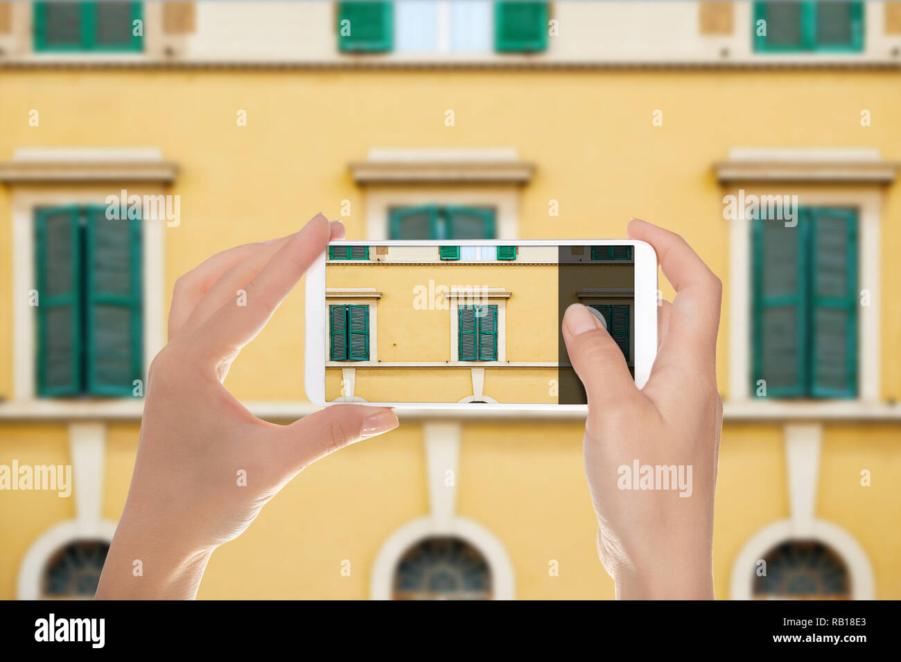 Un uomo è fare una foto del modello da windows della facciata di uno degli edifici in Italia a Roma su un telefono cellulare Foto Stock