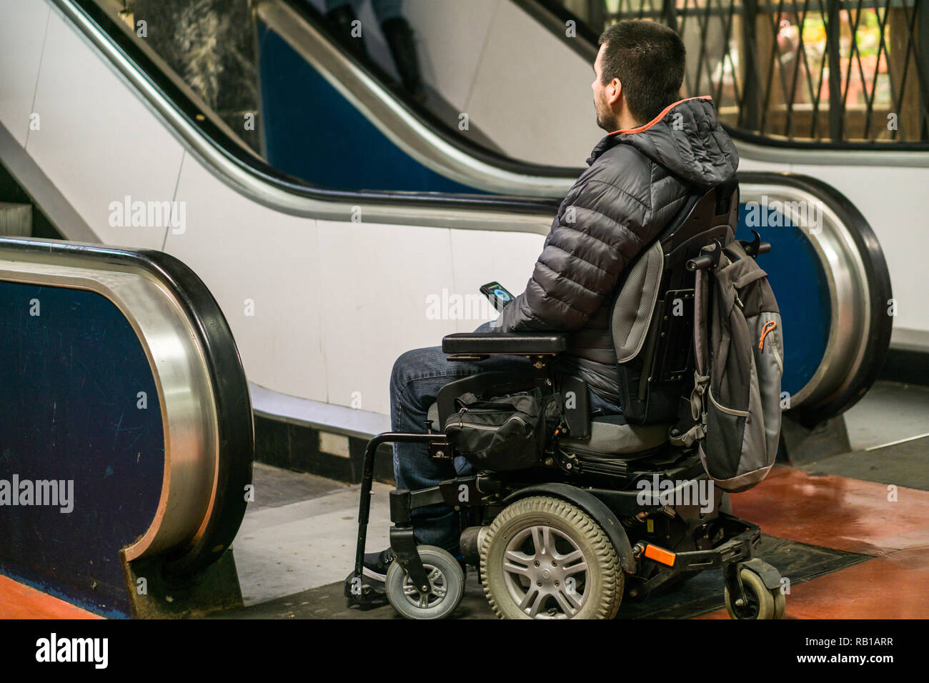 Vista posteriore di un uomo disabili su sedia a rotelle nella parte anteriore delle scale mobili Foto Stock