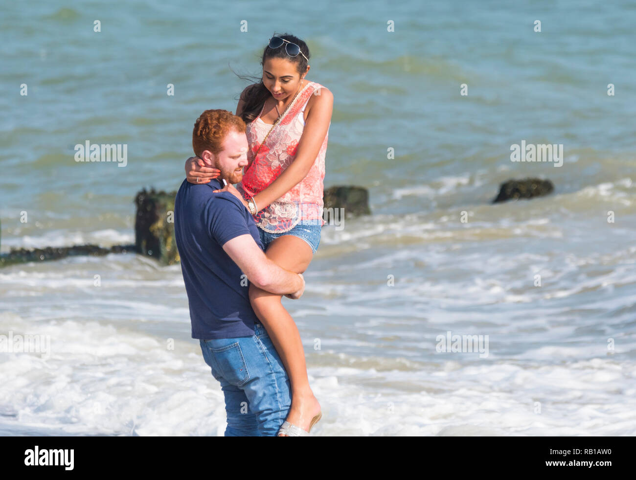 Apparentemente una coppia giovane godendo di essere al mare insieme a una giornata di primavera nel Regno Unito. Foto Stock