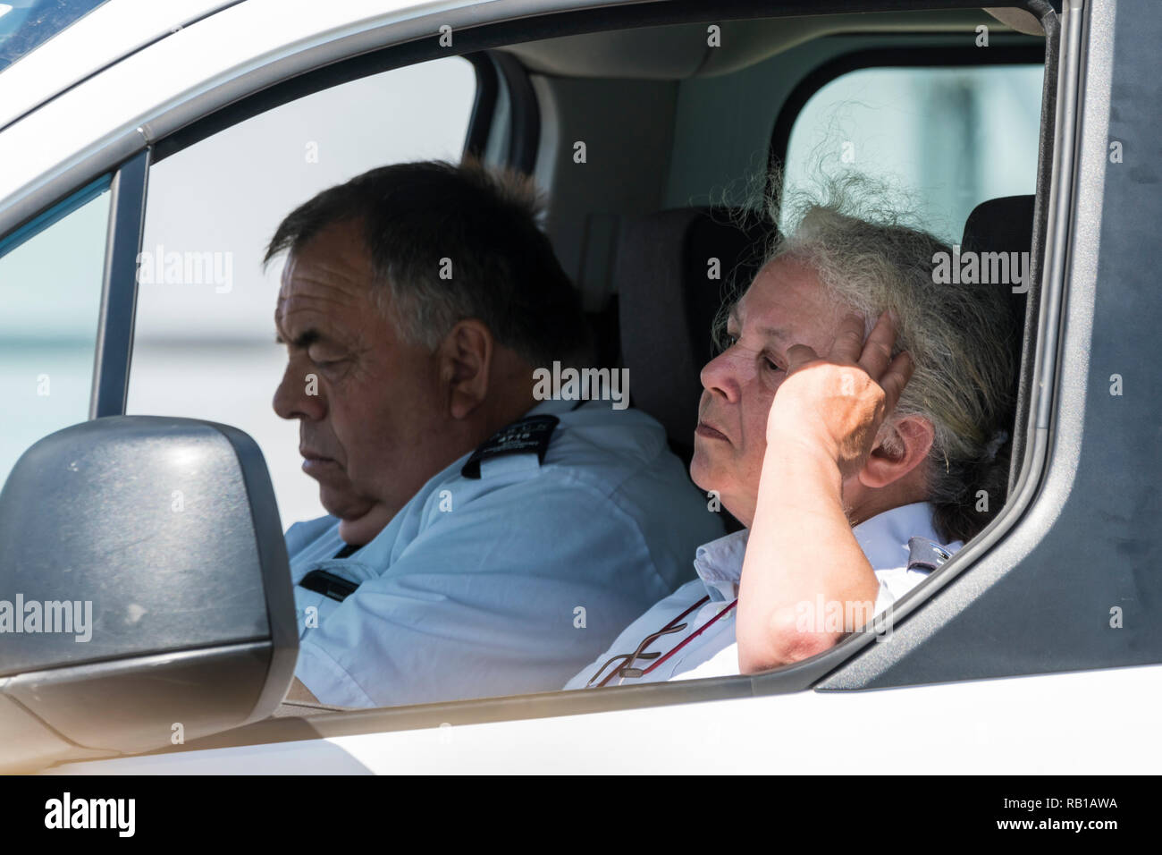 Un paio di persone che guardano annoiati e stufi, appaiono essere parcheggiatori, seduti in un furgone apparentemente guardare fuori per le vittime, nel Regno Unito. Foto Stock