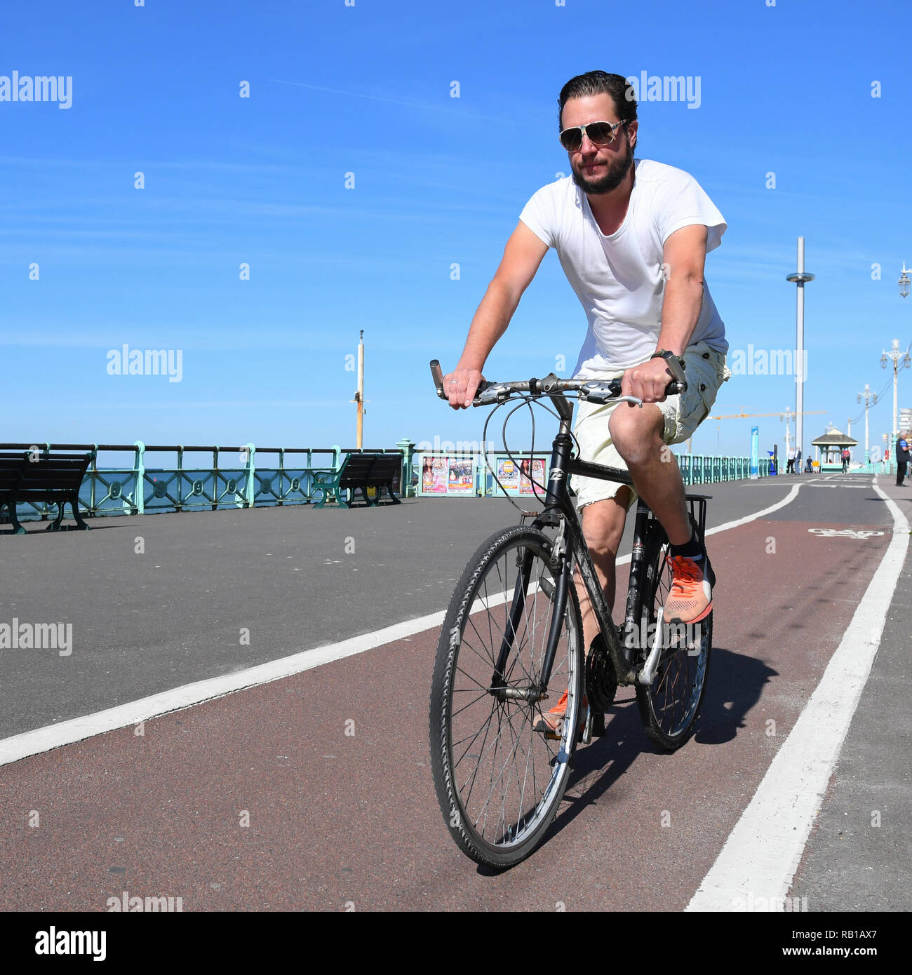 Uomo in 20s o 30s in bicicletta lungo una pista ciclabile sul lungomare di Brighton, East Sussex, Inghilterra, Regno Unito. Foto Stock