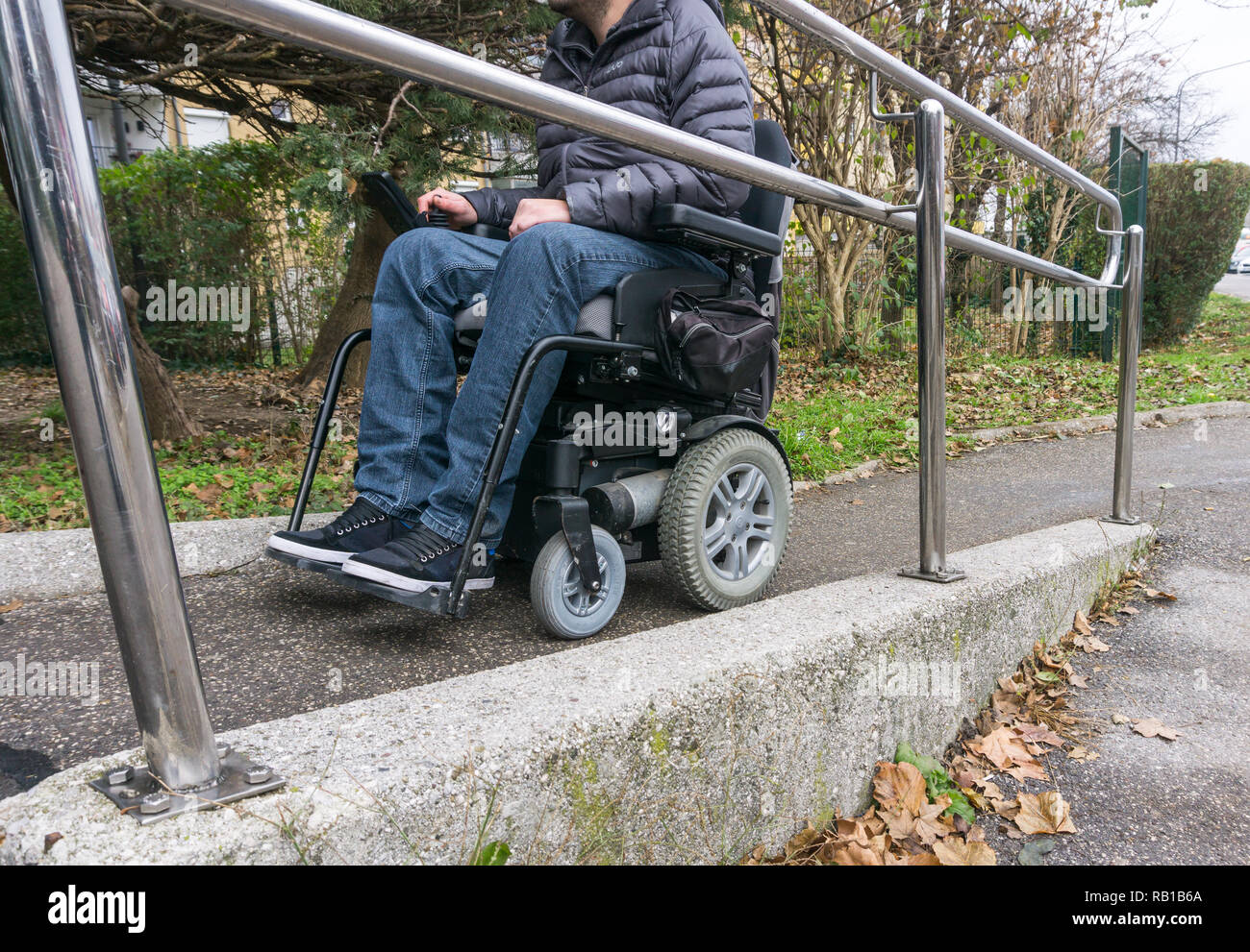 Uomo in sedia a rotelle tramite una rampa accanto alle scale Foto Stock