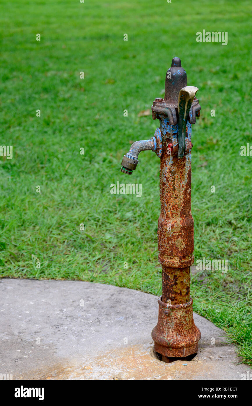 Un ritratto di una verticale e in vecchio stile rustico fontana di acqua realizzato in ferro, con molti punti di ruggine Foto Stock