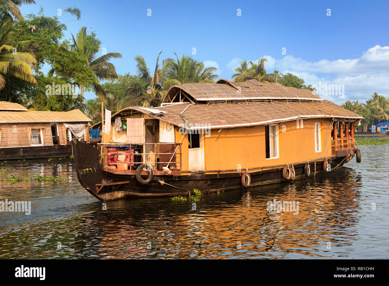 Una casa tradizionale barca è ancorata sulle rive di un lago per la pesca sportiva in Kerala la lagune, India. - Immagine Foto Stock