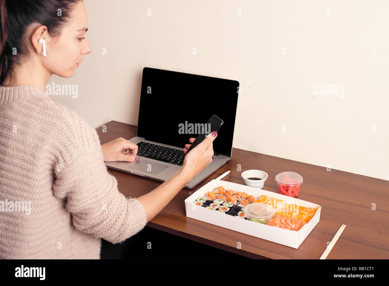 Ragazza di ordinazione online di cibo sul suo smartphone cinese sushi office home Foto Stock