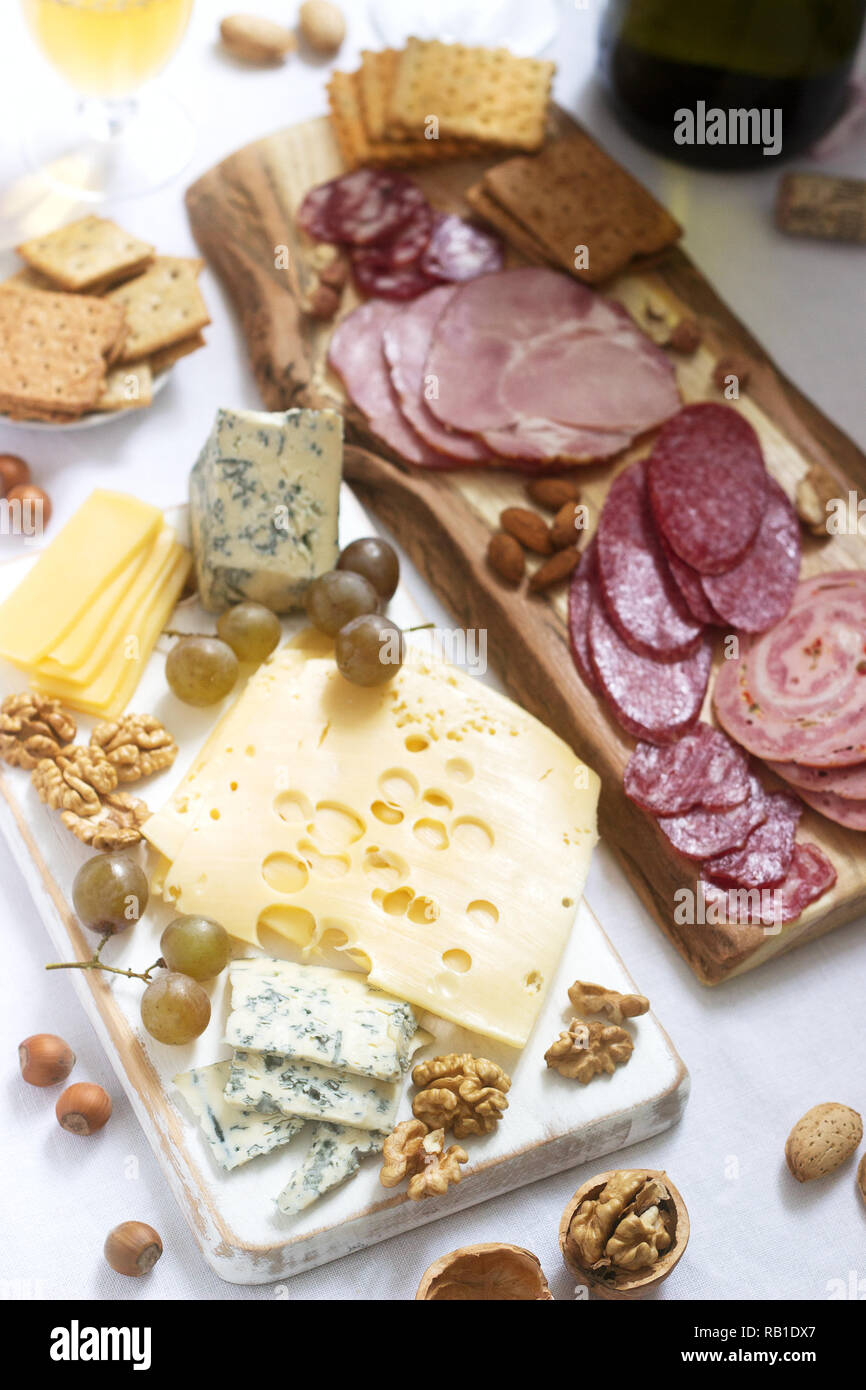 Antipasto di vari tipi di salumi, carni, formaggi e crackers su una tavola di legno, servita al vino. Foto Stock