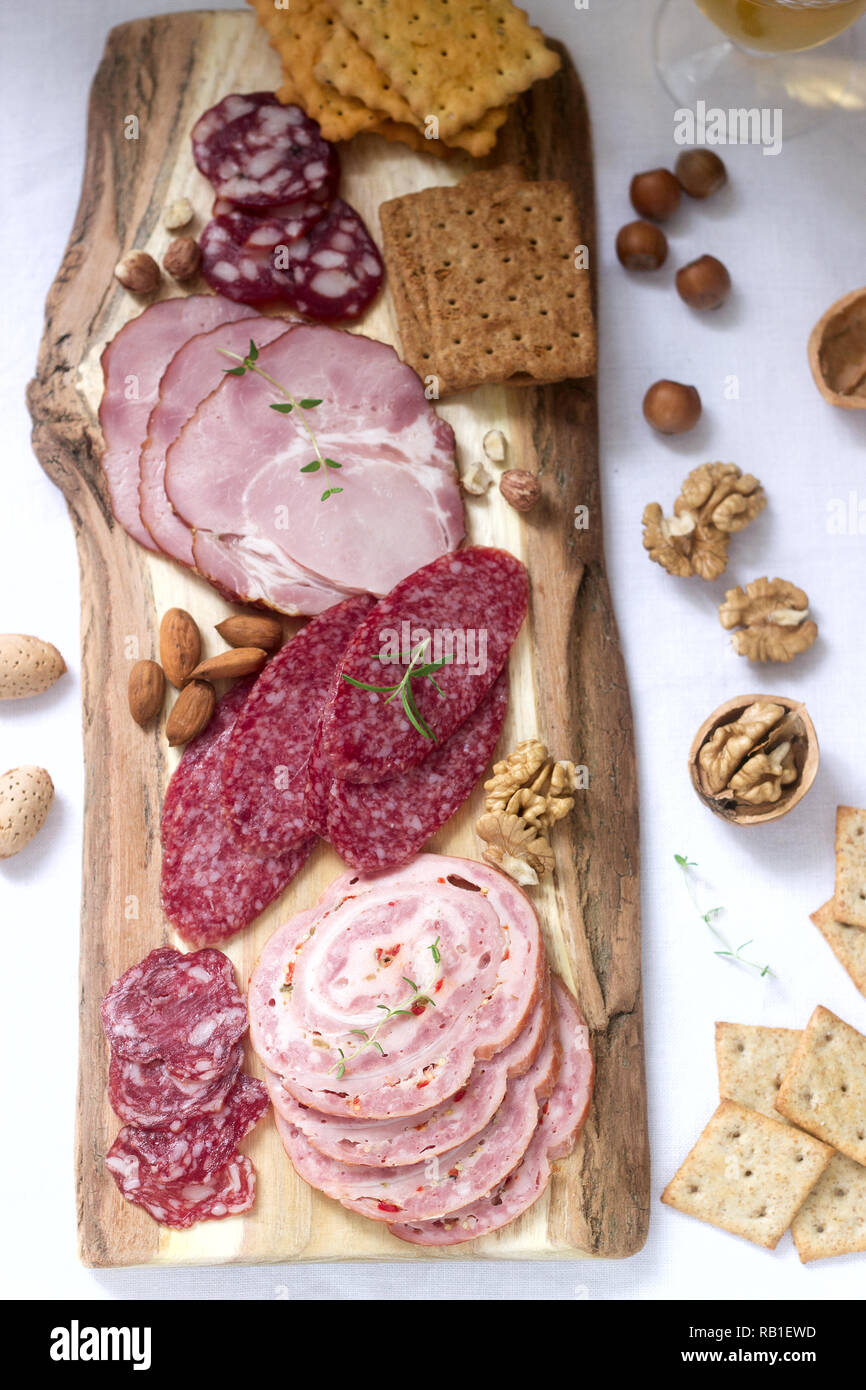 Antipasto di vari tipi di salumi, carni, formaggi e crackers su una tavola  di legno, servita al vino Foto stock - Alamy