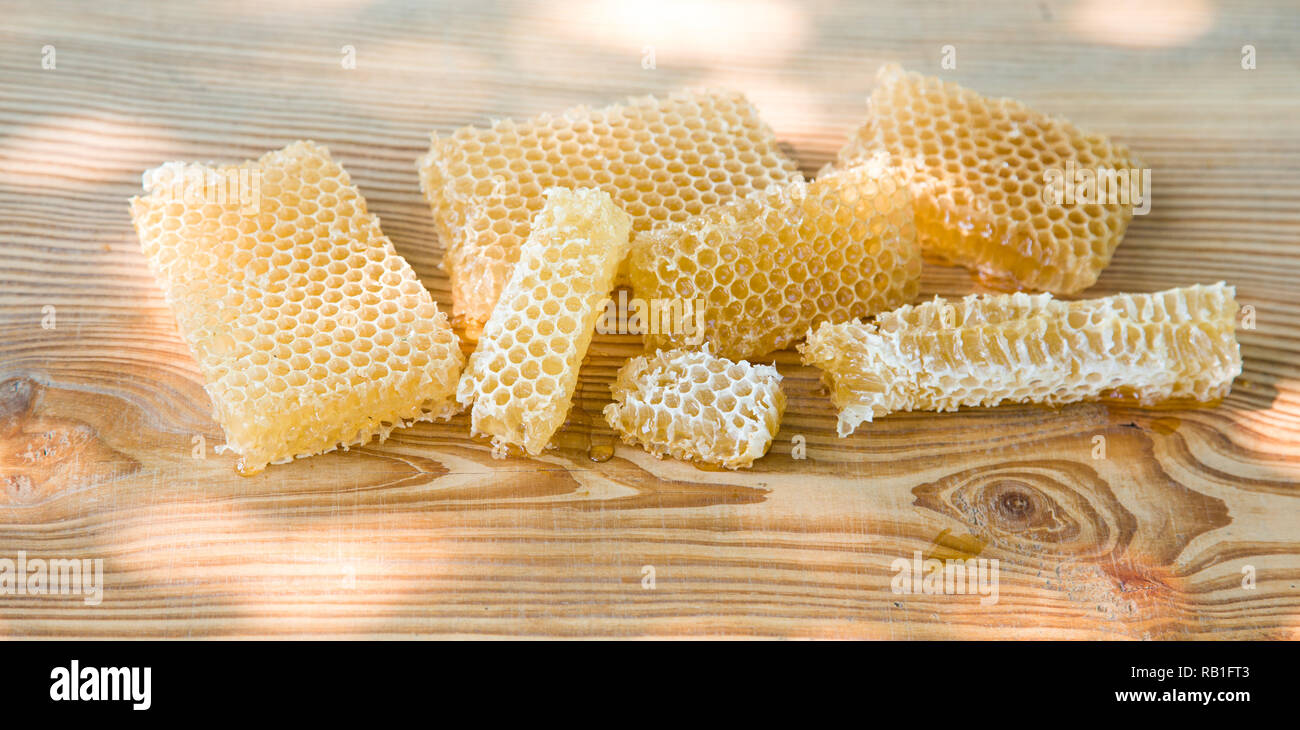 Fresca luce Ape Miele in pezzi di favi su una tavola di legno tavolo rustico con sfocatura dello sfondo. Foto Stock
