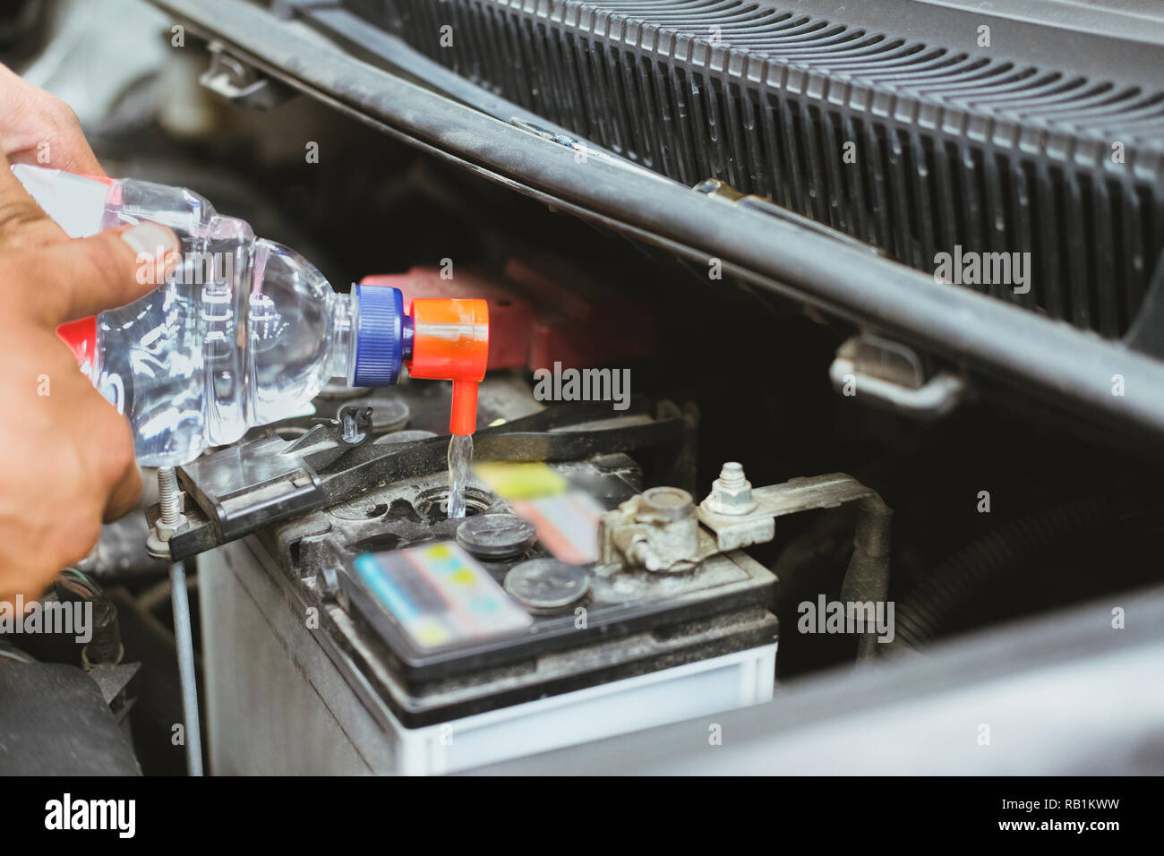Mechanic versando acqua distillata per il riempimento batteria auto in  automobile il servizio di riparazione garage Foto stock - Alamy