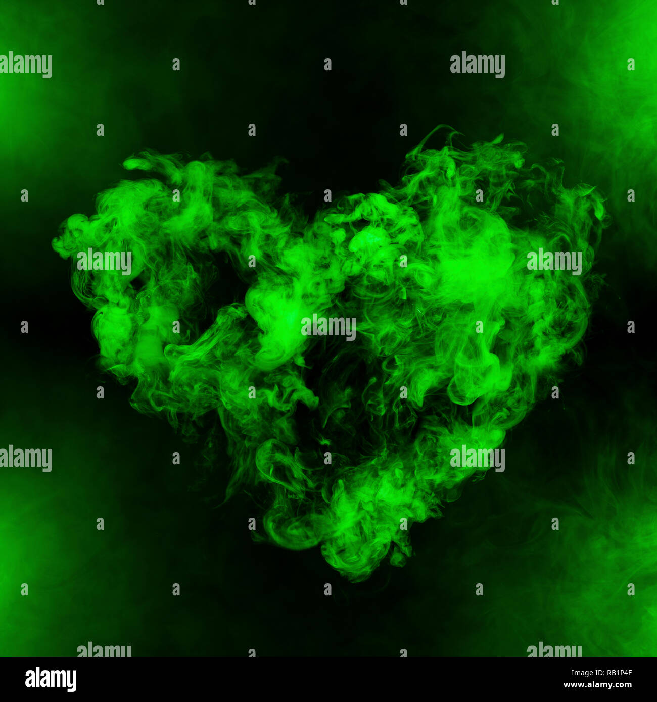 Forma di cuore dal fumo verde isolato su sfondo nero Foto Stock