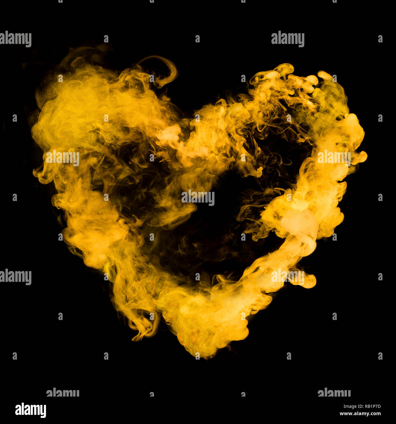 Forma di cuore dal fumo giallo isolato su sfondo nero Foto Stock