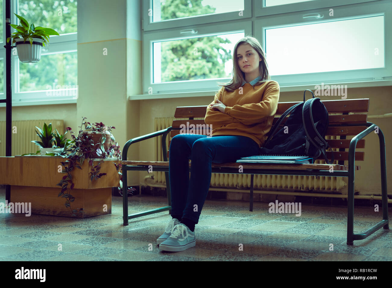 Giovani ansiosi e premuto collegio femminile studente seduto in corridoio alla sua scuola. Istruzione, bullismo, depressione, il concetto di stress. Foto Stock