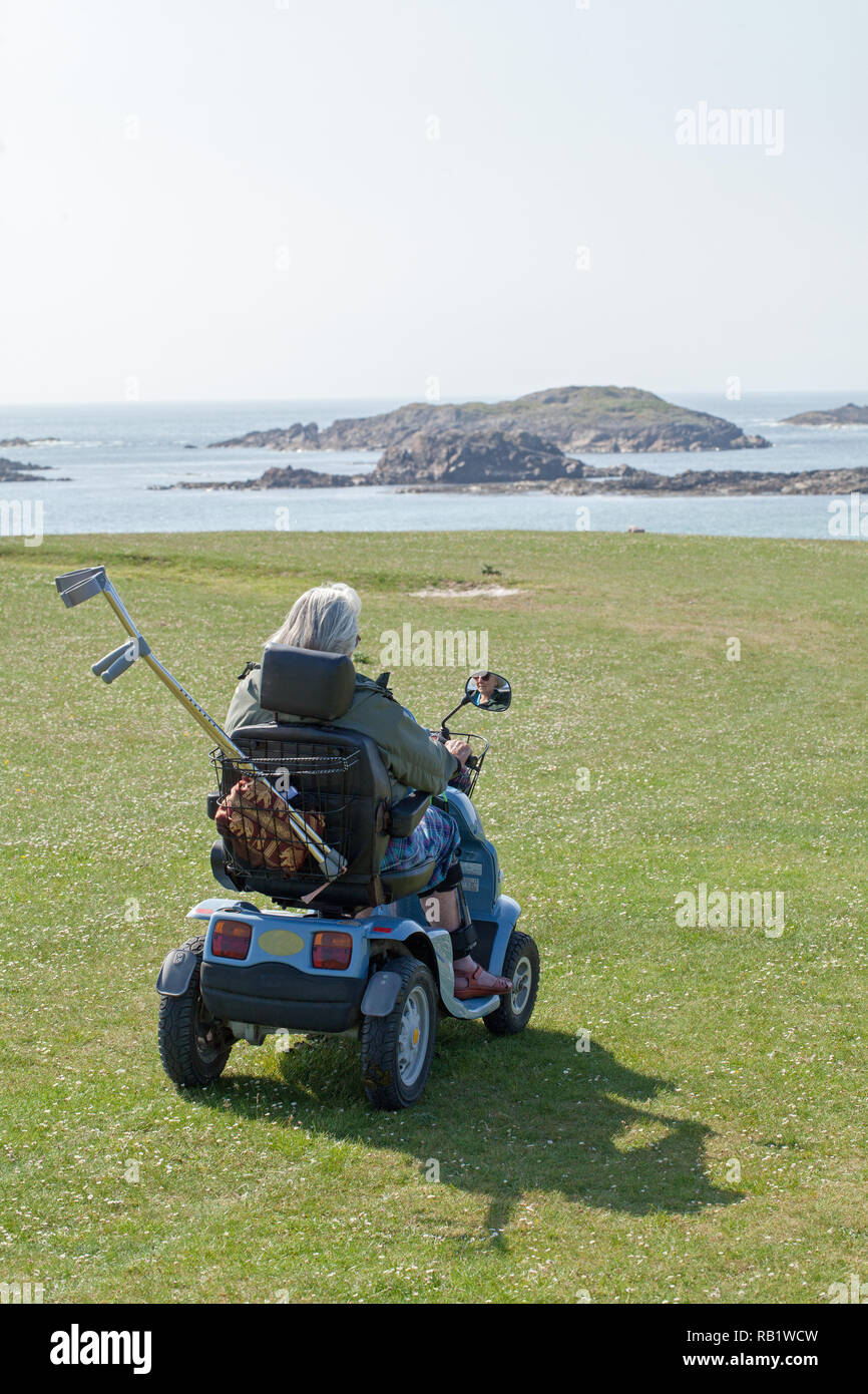 Accesso a una spiaggia di Machair e visualizzare un seascape​,​ da elettrico 'buggy' per disabili o portatori di handicap senior citizen all' Isola di Iona. Il Inner​ Ebridi, Argyll and Bute. Costa ovest della Scozia. Foto Stock