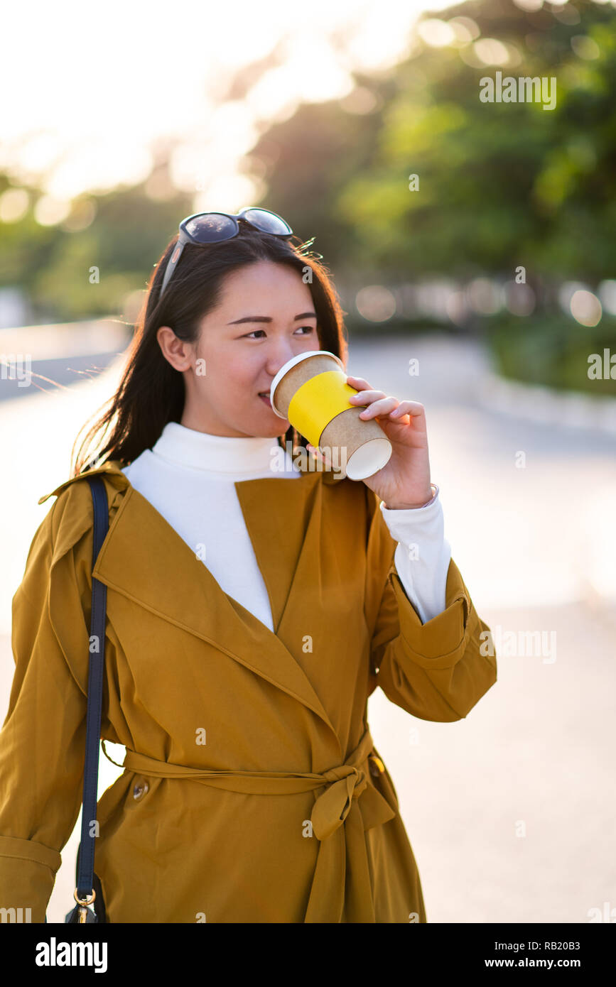 Allegro ragazza con tazza di caffè all'aperto a piedi Foto Stock