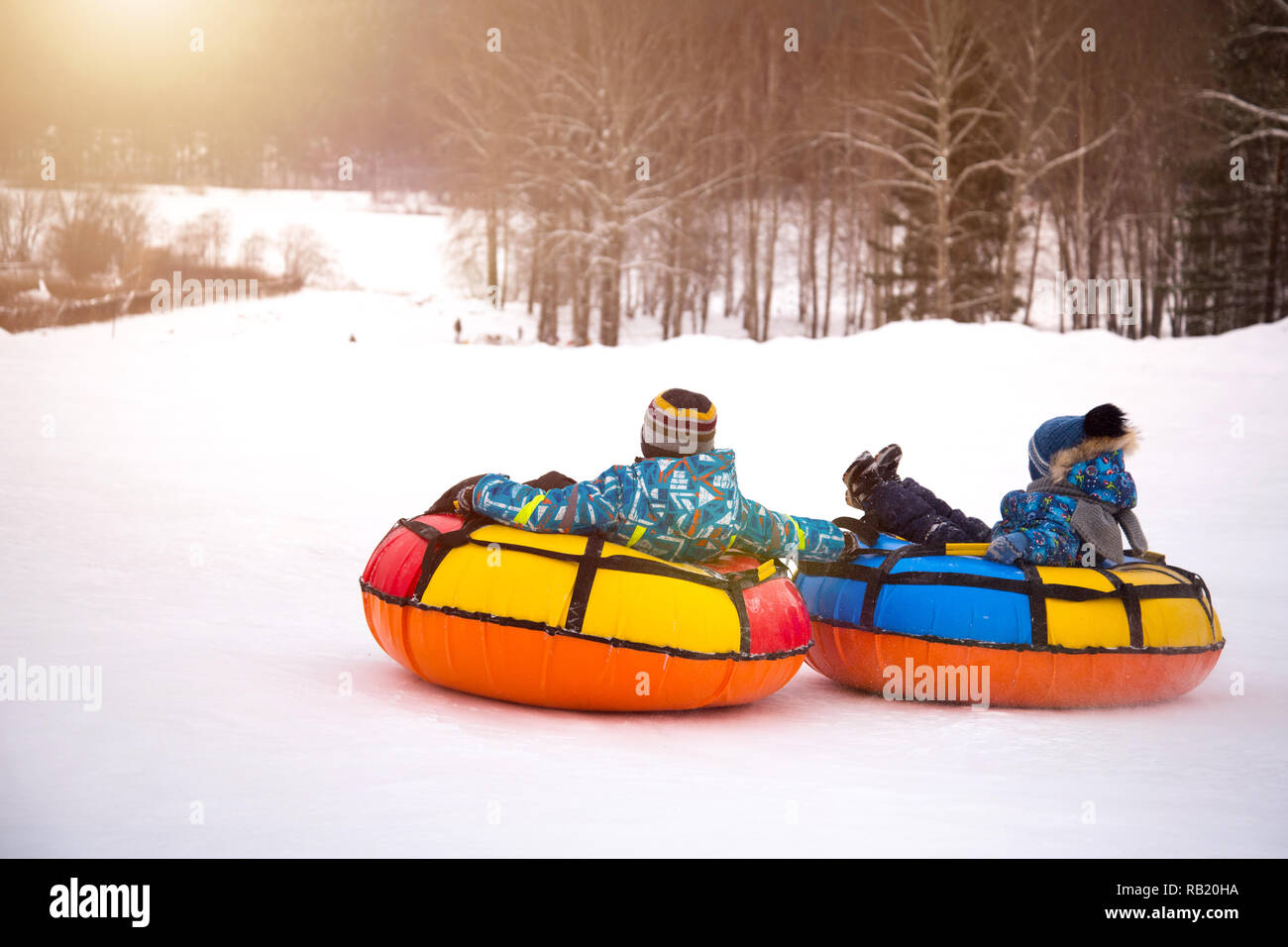 I bambini sono il rotolamento verso il basso snow tubing Foto Stock