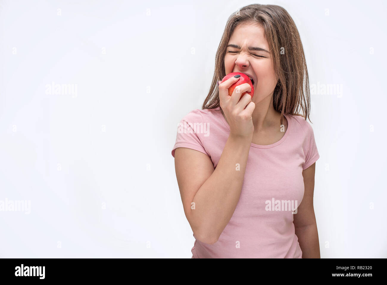 Immagine della giovane donna di mordere il pezzo da apple. Ella si ritira. Iolated su sfondo bianco. Foto Stock
