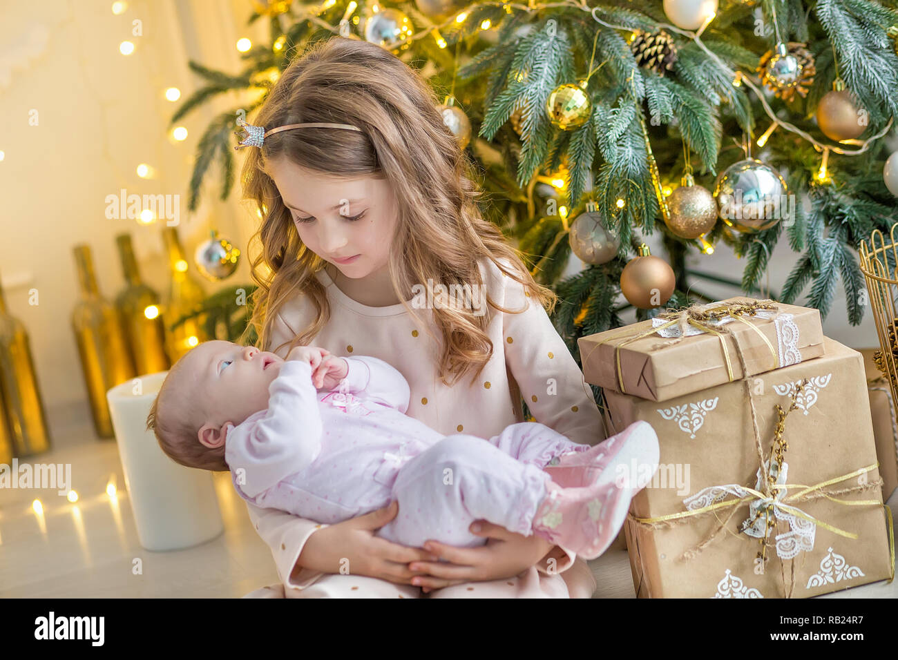 Famiglia alla vigilia di Natale al camino. Kids apertura Xmas presenta. Bambini al di sotto di albero di Natale con confezioni regalo. Decorate soggiorno con tradizione Foto Stock