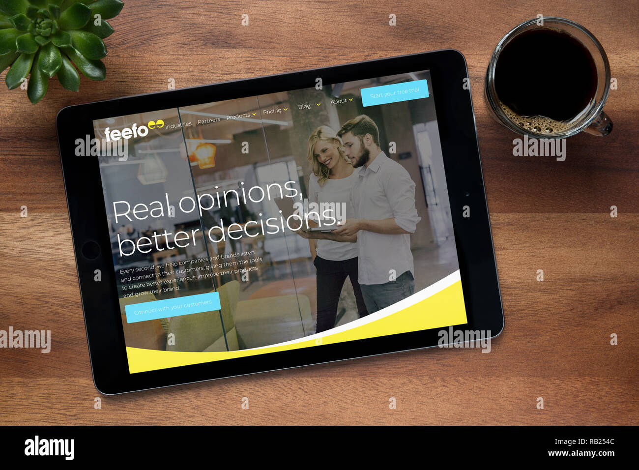 Il sito web di Feefo è visto su un tablet iPad, su di un tavolo di legno lungo con un caffè espresso e una pianta di casa (solo uso editoriale). Foto Stock