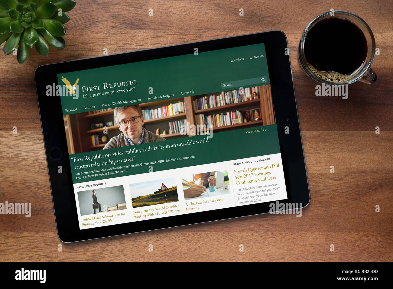 Il sito web della Prima Repubblica Banca è visto su un tablet iPad, su di un tavolo di legno lungo con un caffè espresso e una pianta di casa (solo uso editoriale). Foto Stock