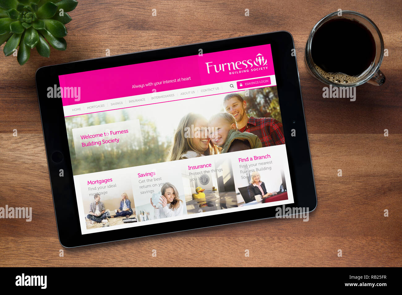 Il sito web di Furness Building Society è visto su un tablet iPad, su di un tavolo di legno lungo con un caffè espresso e una pianta di casa (editoriale solo) Foto Stock